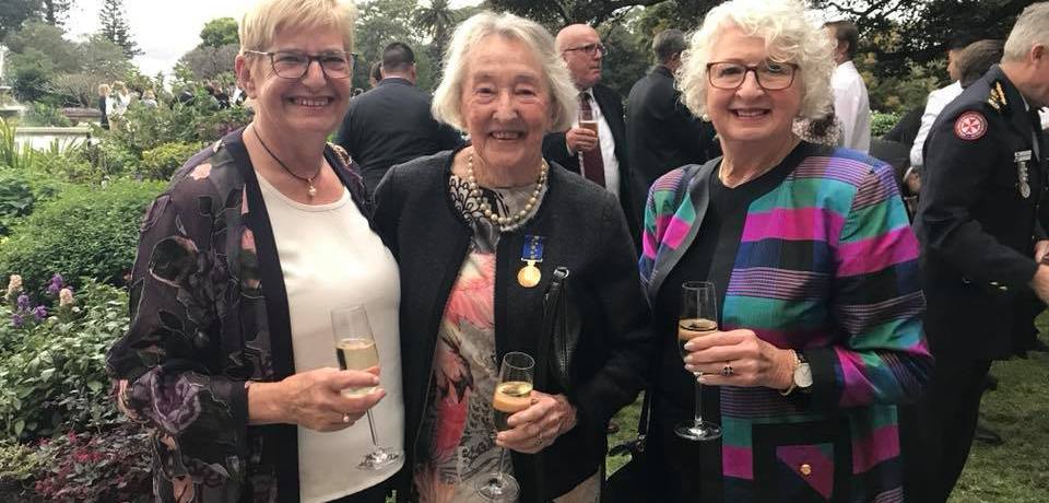 Picture of three well dressed women with glasses of champagne celebrating in the garden of Government House