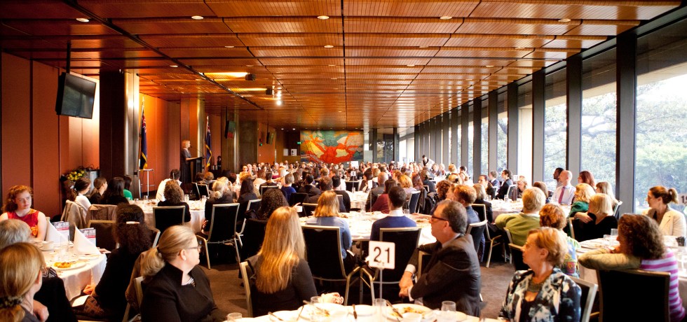 Picture of people listening to a speaker and sitting at a number of tables