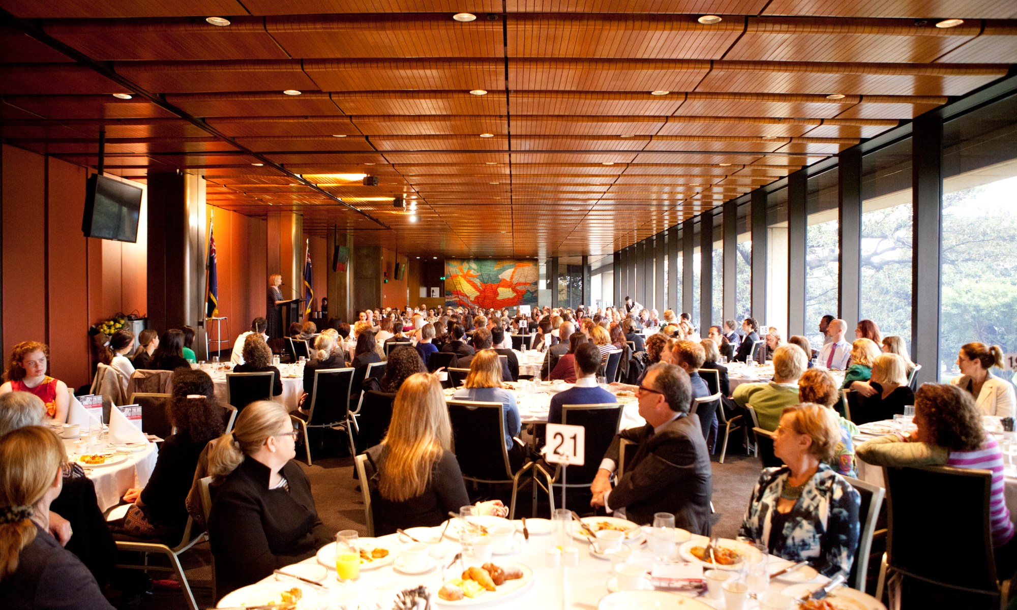 Picture of people listening to a speaker and sitting at a number of tables